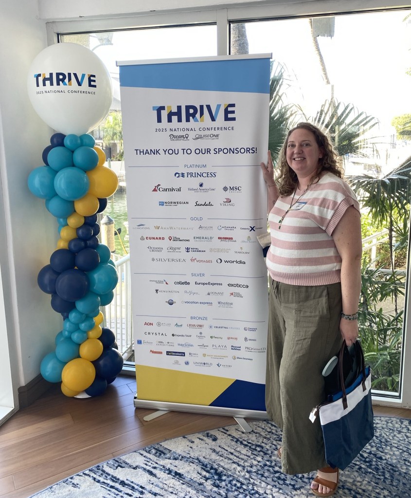 Allison in front of sponsor sign at 2025 National Conference. 